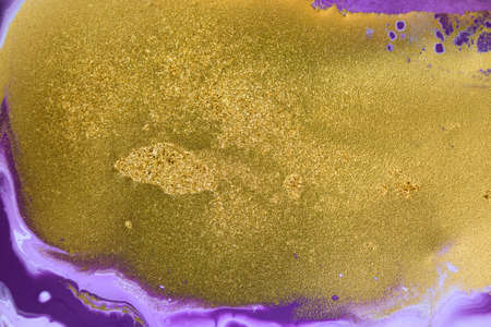 Cose up gold glitter on liquid mixed purple inks background.の写真素材