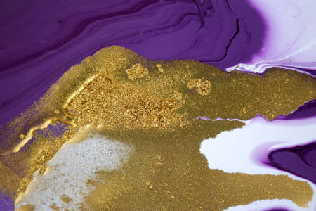 Cose up gold glitter on mixed inks background.