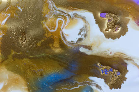 Piles of gold sequins on white and blue smudges of paint background. Abstract pattern.