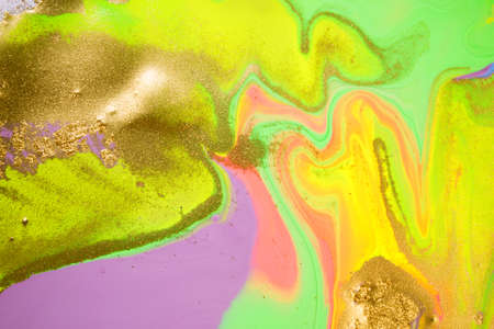 Streams of liquid fluorescent and gold ink curls. Waves of fluid vivid golden fluid paint.