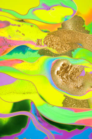 Gold dust and waves on fluorescent inks background.の写真素材