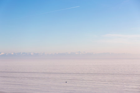 Frozen Lake covered with snow. Snow capped mountains on the horizon.の写真素材