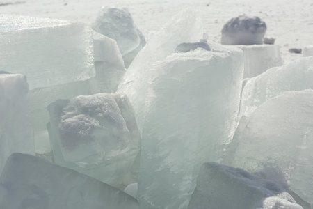 Transparent blue ice hummocks on lake Baikal shore. Siberia winter landscape view. Snow-covered ice...