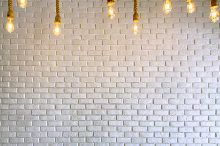 White Brick Wall with Burning Glass Light Bulbsの写真素材