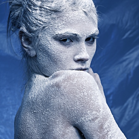 Portrait of a beautiful girl in the frost on his face on a blue ice backgroundの写真素材