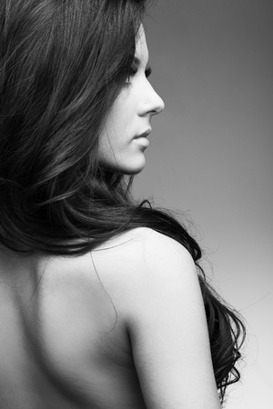 beautiful woman with perfect skin and long dark luxuriant hair on a dark backgroundの写真素材