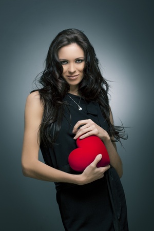 Valentine s Day  Beautiful smiling woman with a gift in the form of heart in his handsの写真素材