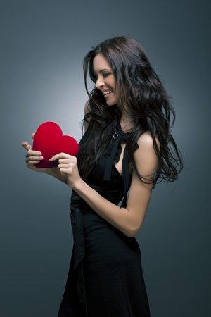 Valentine s Day  Beautiful smiling woman with a gift in the form of heart in his handsの写真素材