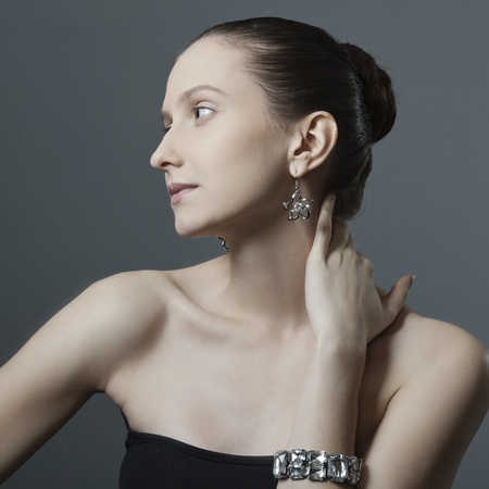 beautiful woman with perfect skin, bare shoulders in the jewelry on a dark backgroundの写真素材