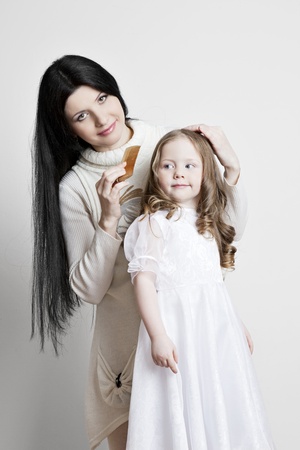 Portrait of a beautiful mother and daughter in his arms on a white backgroundの写真素材