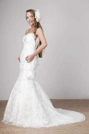 beautiful smiling girl in a white wedding dress on a gray backgroundの写真素材