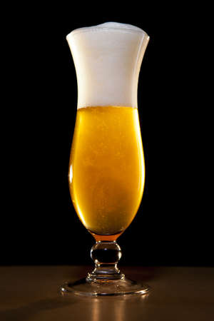 a blond beer in a stylish glass, the ferment is spreading in the glassの写真素材