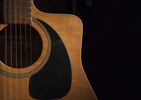 a close up view of a acoustic guitar on a black backgroundの写真素材