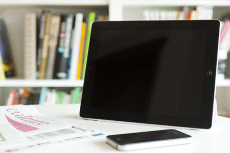 A ipad2 tablet and newspaper and iphone, books on the background
