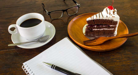 A delicious cake with a coffee and the pocketbook.の写真素材