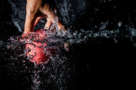 hand pick up apple on water splash, black wallpaperの写真素材