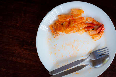 Shrimp pile shell waste after eating on white dish, on the tableの写真素材