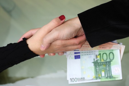 businessmen and businesswoman handshake with  money on desk
