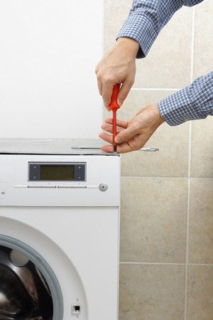 Technician servicing washing machine using screwdriverの写真素材
