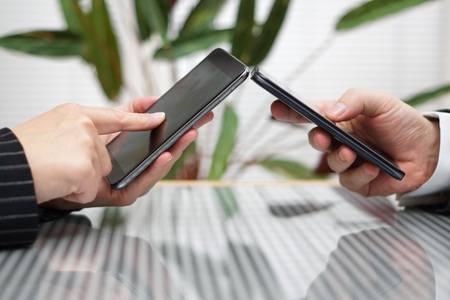woman and man transferring files from smart mobile phone to another