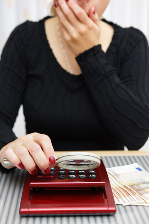 woman watching sum on calculator with magnifying glass and cant believe numbers on itの写真素材