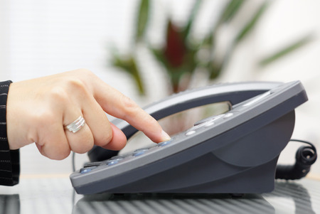 businesswoman is dialing on landline telephoneの写真素材