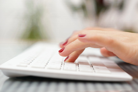 female fingers typing on white keyboardの写真素材