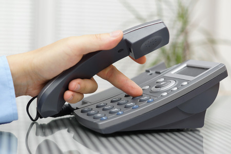 businessman hand is dialing a phone number with picked up headsetの写真素材