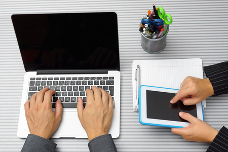 top view of businesswoman and businessman on meeting working with tablet computer and typing on laptopの写真素材
