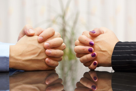 Man and woman sits at a desk with hands clasped. marital problems, conflicts and stubborn conceptの写真素材