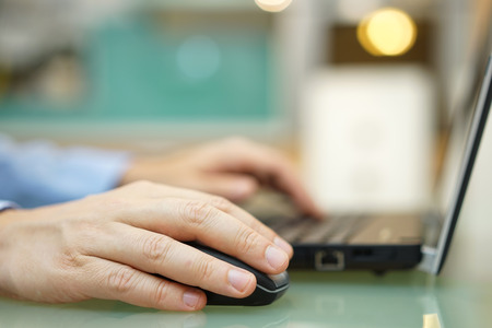 Man is working on laptop at home. Shallow depth of field , focus on mouseの写真素材