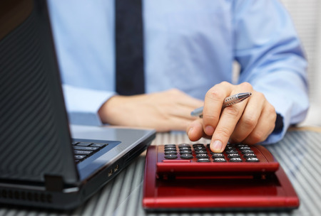 Closeup of businessman working on calculator and laptopの写真素材