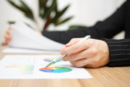 Businesswoman reviewing report and browsing documentの写真素材