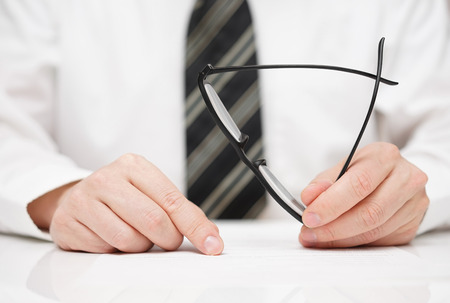 Businessman with glasses in hand is carefully reading contractの写真素材