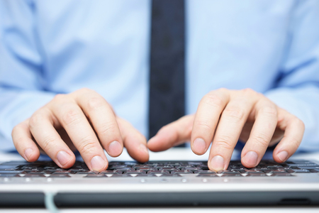 Businessman in blue shirt typing on computer keyboardの写真素材