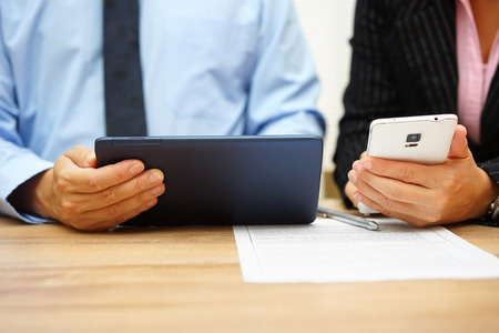 closeup of business people hands working and analyzing data on tablet pc and smart mobile phoneの写真素材