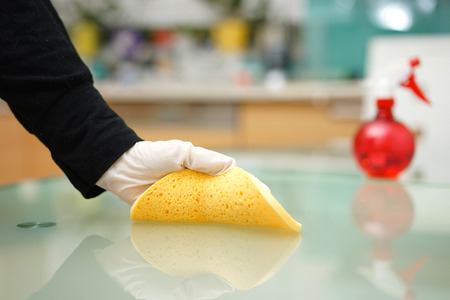 woman is cleaning table in kitchen woth spongeの写真素材