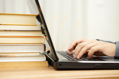 Student is using laptop and books to prepare for examの写真素材