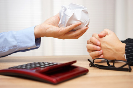 manager is giving back crumpled document to employeeの写真素材