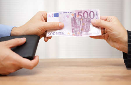 Closeup of man giving woman money from walletの写真素材
