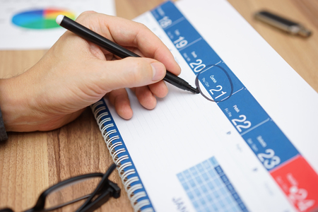 Businessman is setting an important date on a calendar with a marker. Concept of plan,organize,importanceの写真素材