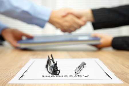 businessman and businesswoman are shaking hands and exchanging folder  after agreement was reached