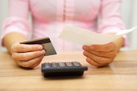 woman is holding bill and credit card in hands  and calculating the costsの写真素材