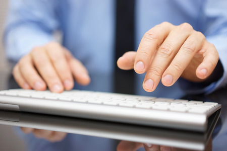 Closeup of businessman typing on modern computer keyboardの写真素材