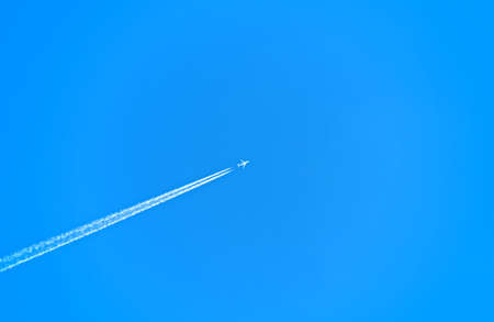 Jet Airplane with Vapor Trail Behide Isolated on Clear Blue Skyの写真素材