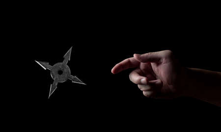 Closeup Hand Throwing Ninja Star Shuriken Isolated on Black Backgroundの写真素材