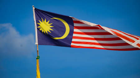 Malaysian flag from left to right with blue sky in the backgroundの写真素材