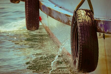 Side view of two wheels protecting the boat with water splashingの写真素材