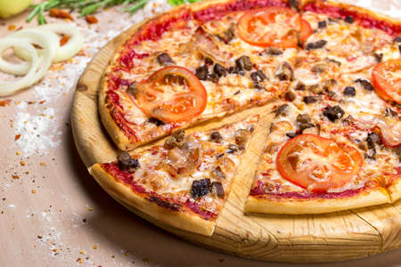 Tasty pizza, tomatoes and others ingredients on a wooden background.の写真素材
