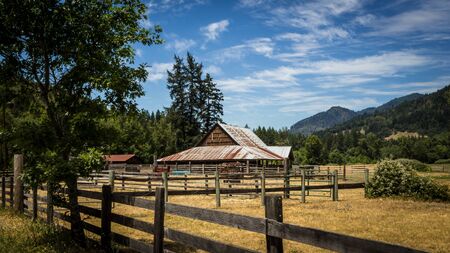 Landscape image of a fenced farm and barn on a sunny dayの写真素材